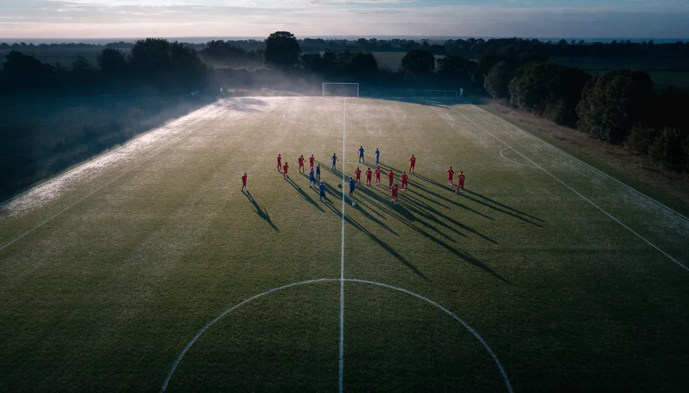 Ein Fussballplatz von oben gesehen, die Linien bilden ein helles Muster auf dem Rasen, Drohnenperspektive in der Morgendämmerung.
